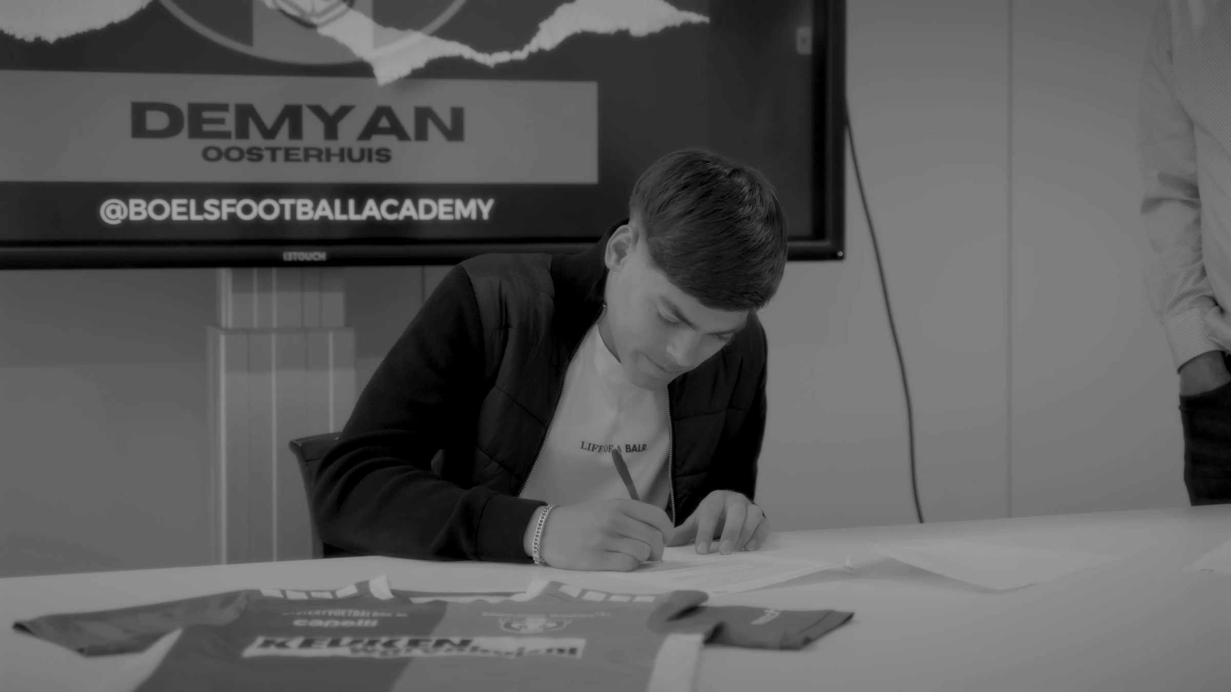 Demyan tekent zijn contract onder het bord met zijn naam